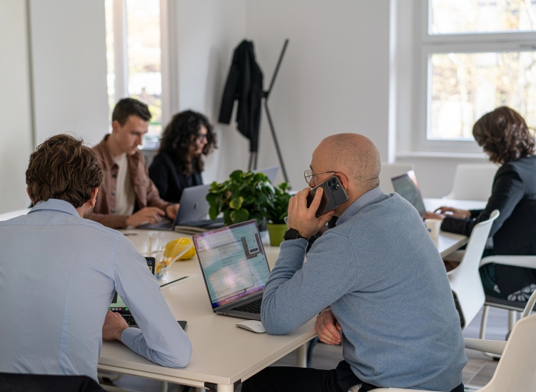 Persone al lavoro in un ufficio con computer portatili.