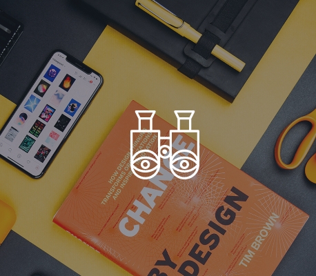 Scrivania Creativa con Oggetti di Design Scrivania con libro 'Change by Design', smartphone, quaderno e forbici.