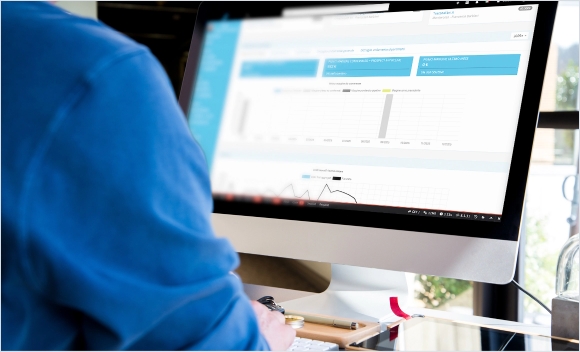 Persona al computer che analizza dati su uno schermo con grafici e tabelle.