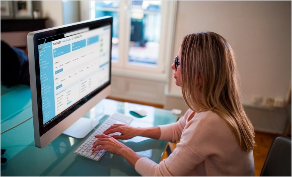 Donna che lavora al computer su un’interfaccia web in un ufficio ben illuminato.