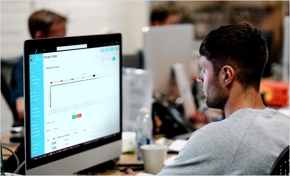 Uomo che osserva un grafico sul monitor del computer in un ufficio.